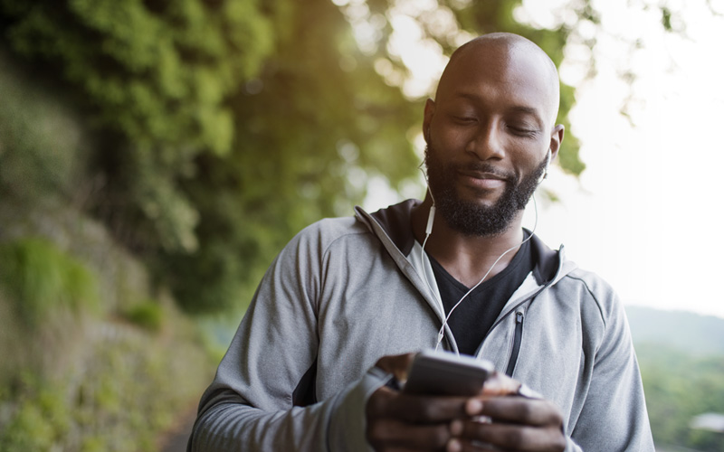 Man walking outdoors while viewing his cellphone