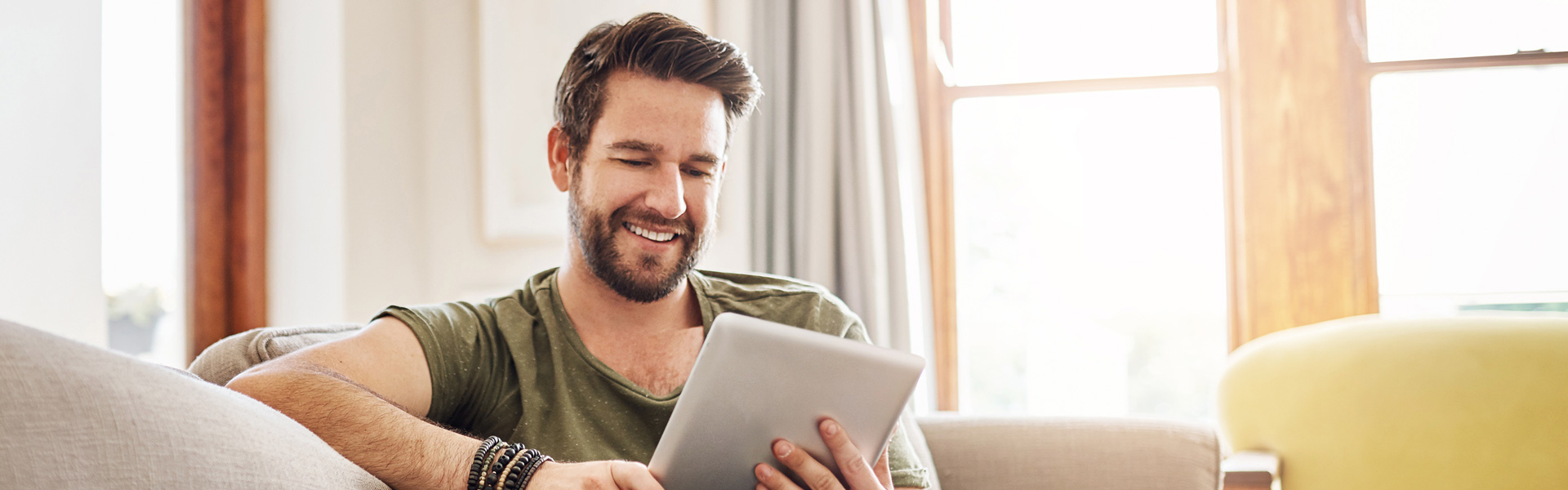 Man sitting on a couch viewing a tablet