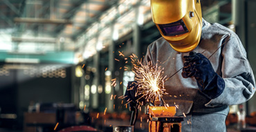 Welder welding with yellow protective helmet