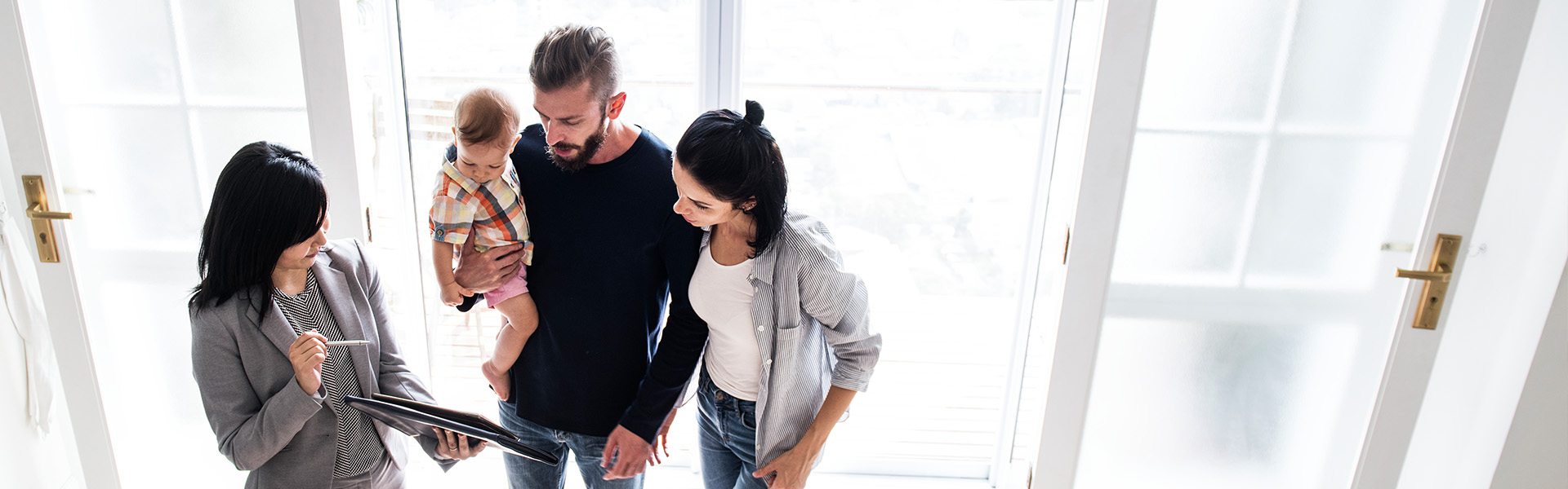 Young Family Conversing with Real Estate Professional in Entryway of a Home