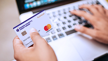 hand holding credit card with other hand on laptop keyboard