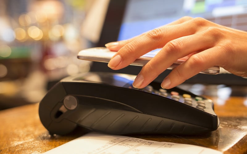 Hand holding phone over payment terminal