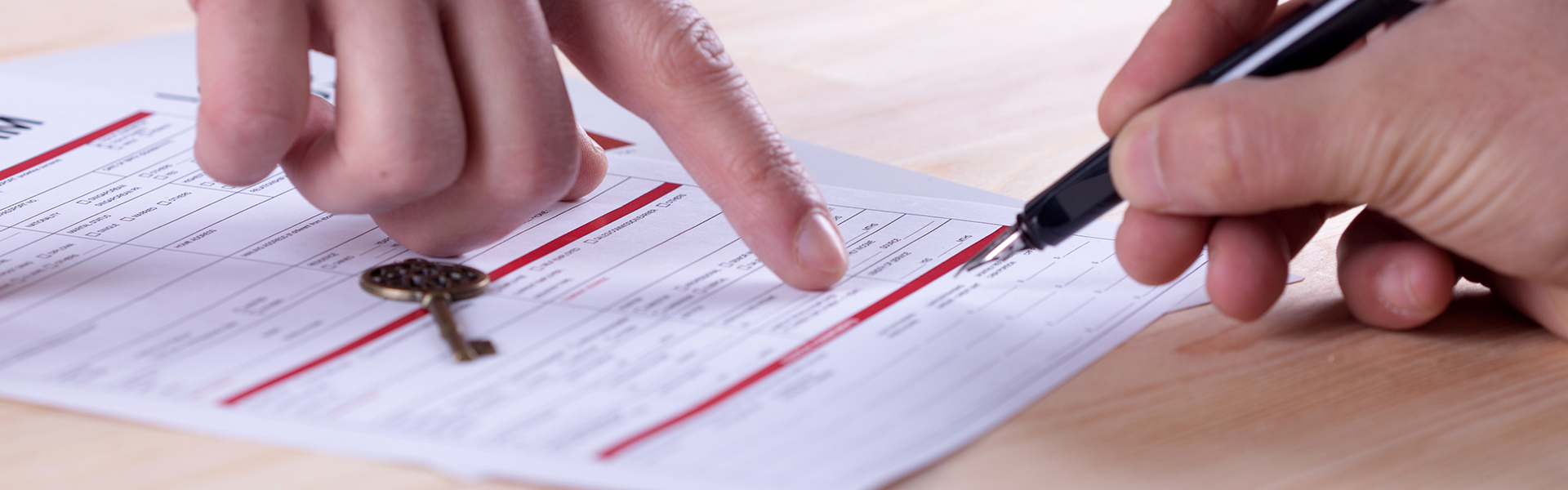 Close up of hand signing red and white mortgage document with calligraphy pen.