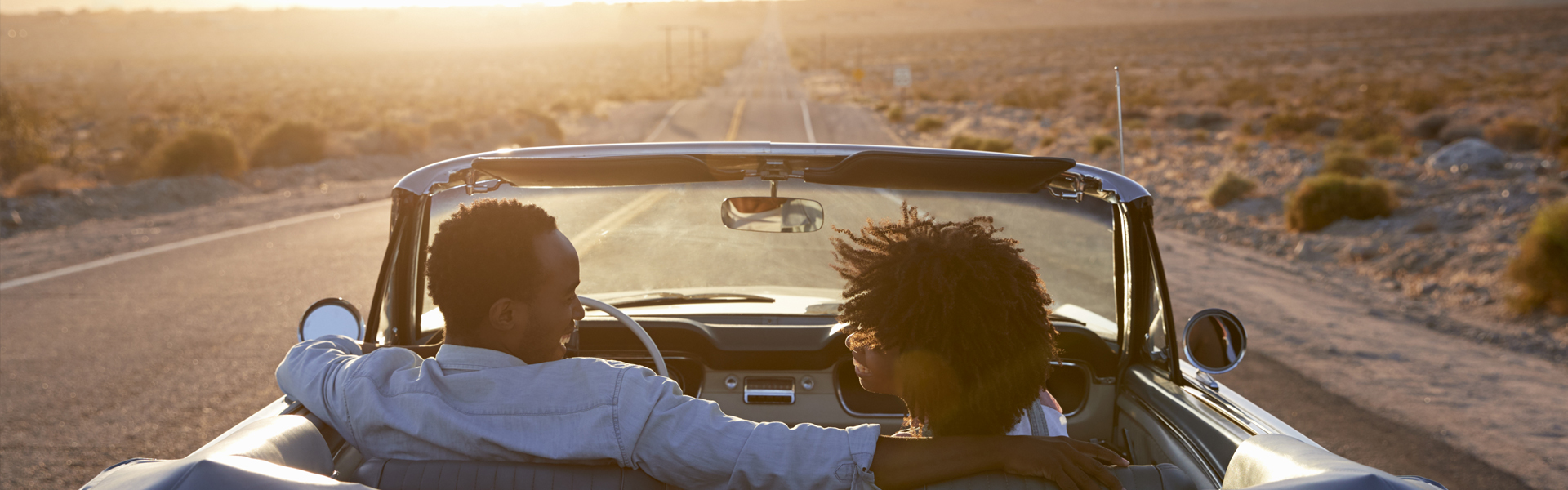 smiling driver and passenger in a convertible car