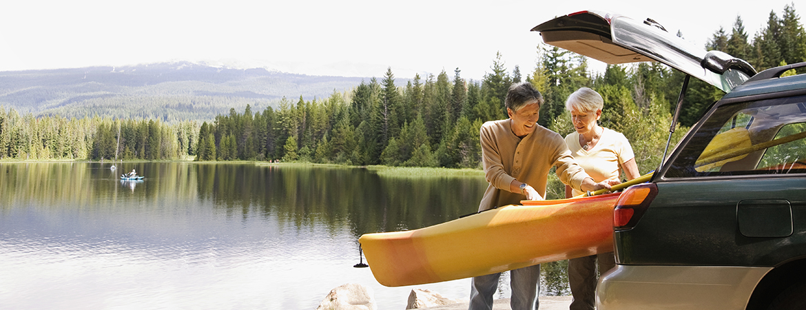 Mature age couple unloading canoe at a lake