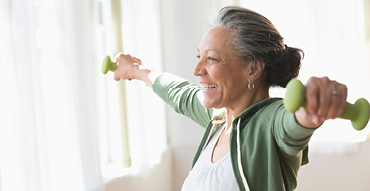 Senior woman holding barbells doing arm exercises