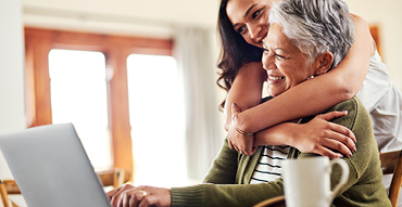 Grown daughter hugging senior mother with both smiling