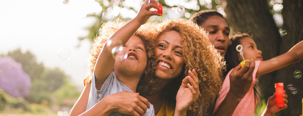 Parents with their two young children playing with bubbles in the park