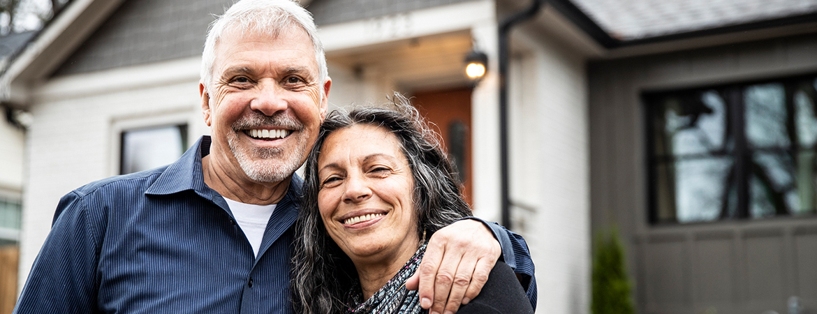 Smiling couple standing in front of their home